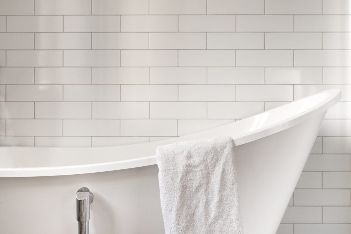 WHat's the best way to clean a bathtub? A clean, white bathtub on front of white subway tile.