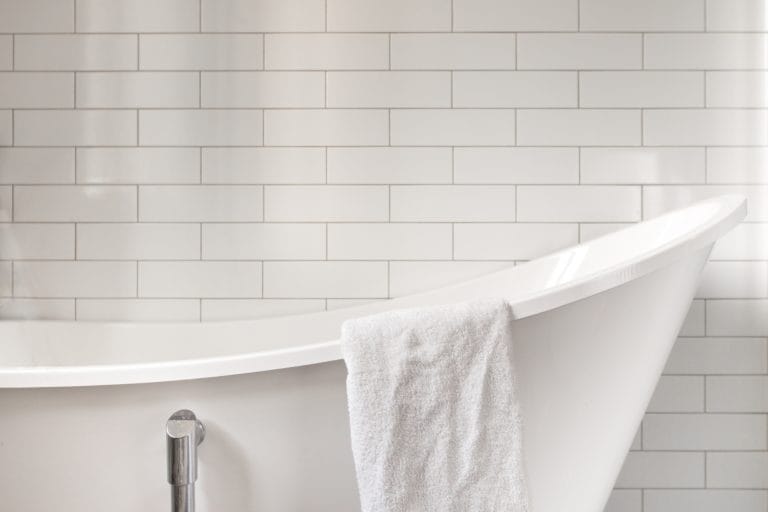 WHat's the best way to clean a bathtub? A clean, white bathtub on front of white subway tile.