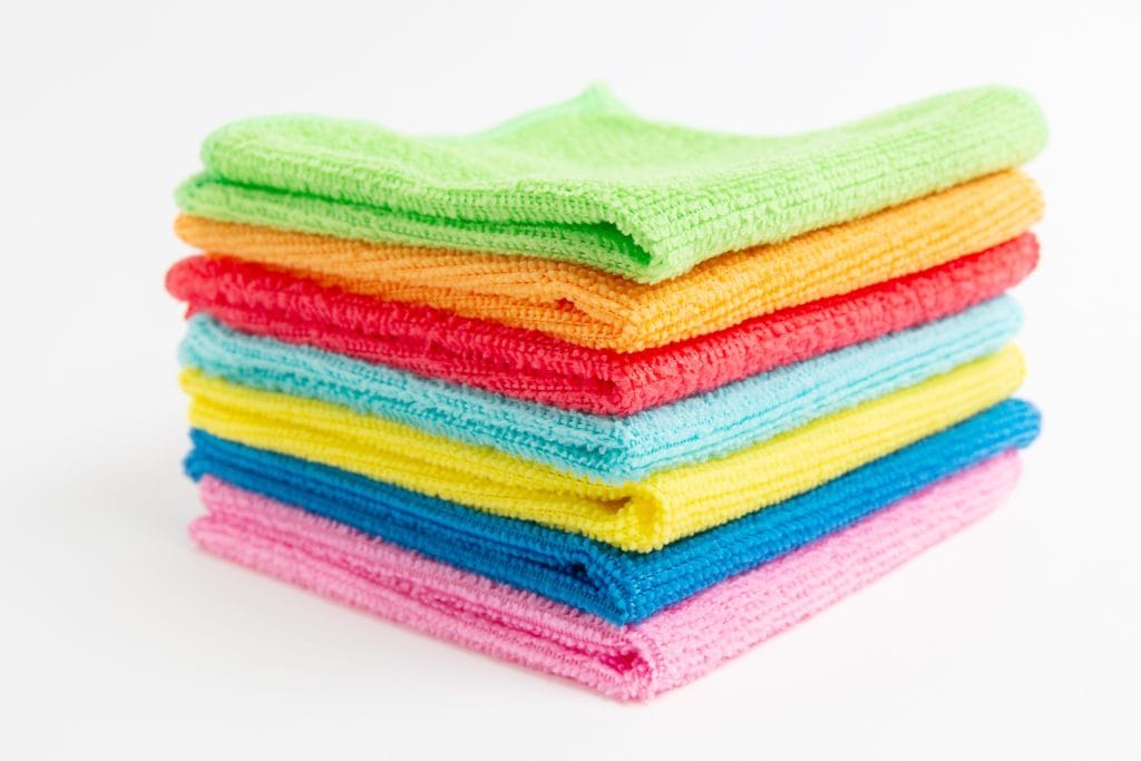 A stack of colorful microfiber cloths for cleaning the grease off kitchen cabinets