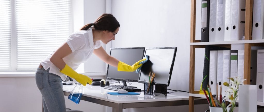 A woman cleaning a computer screen.