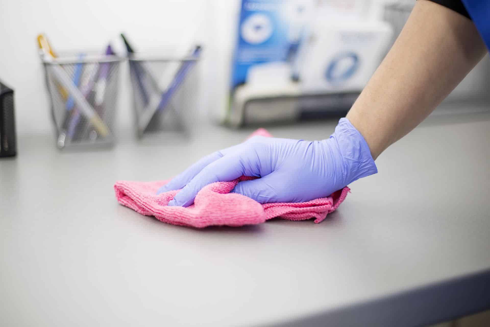 a gloved hand wiping an office desk