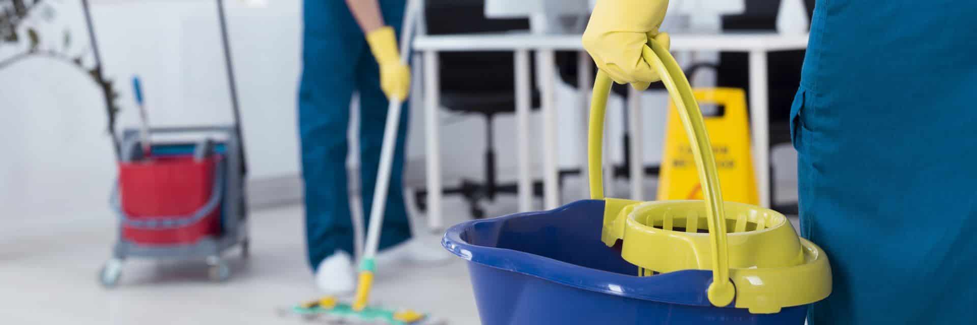person holding blue cleaning bucket with yellow glove on 