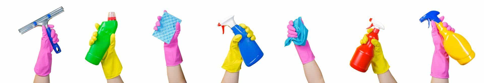 pink and yellow gloved hands holding up a variety of cleaning products