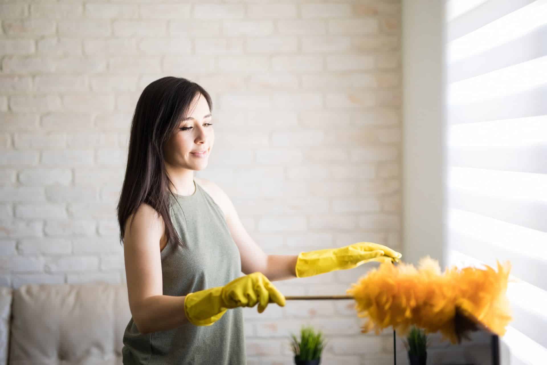 How Often You Should Really Be Dusting Your Home 2 woman using a yellow feather duster to dust her home