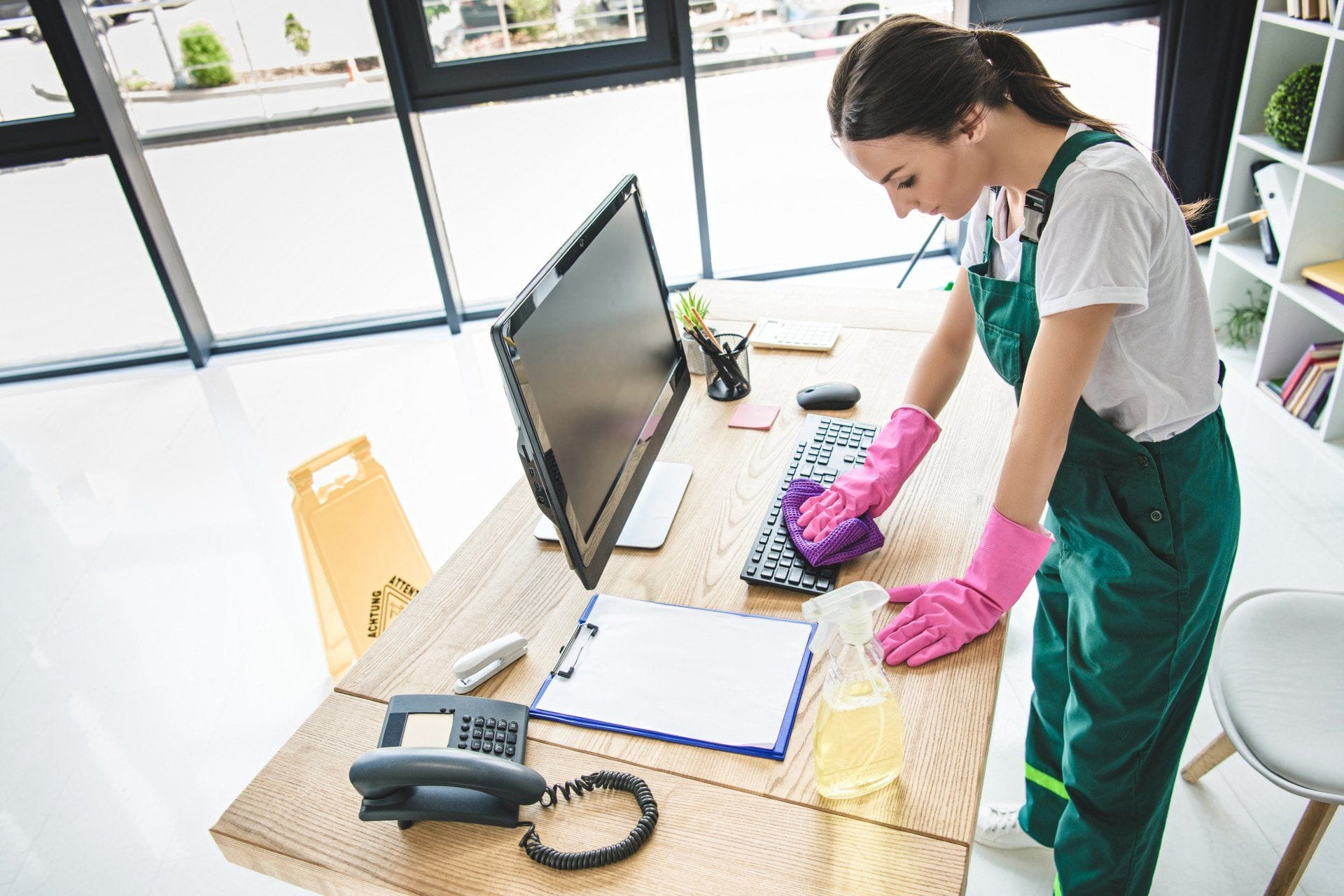 a cleaner wiping down a keyboard on a company desk