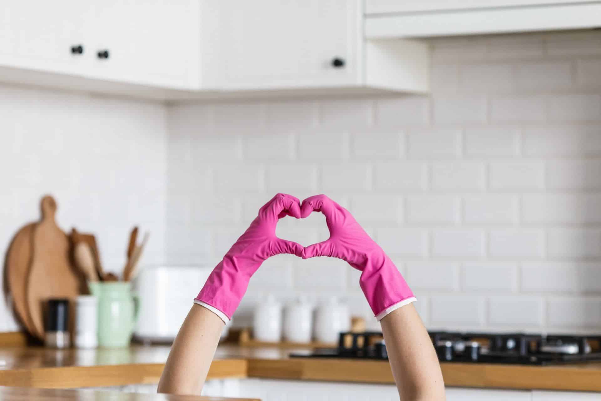 a person making the shape of a heart with their hands while wearing pink gloves