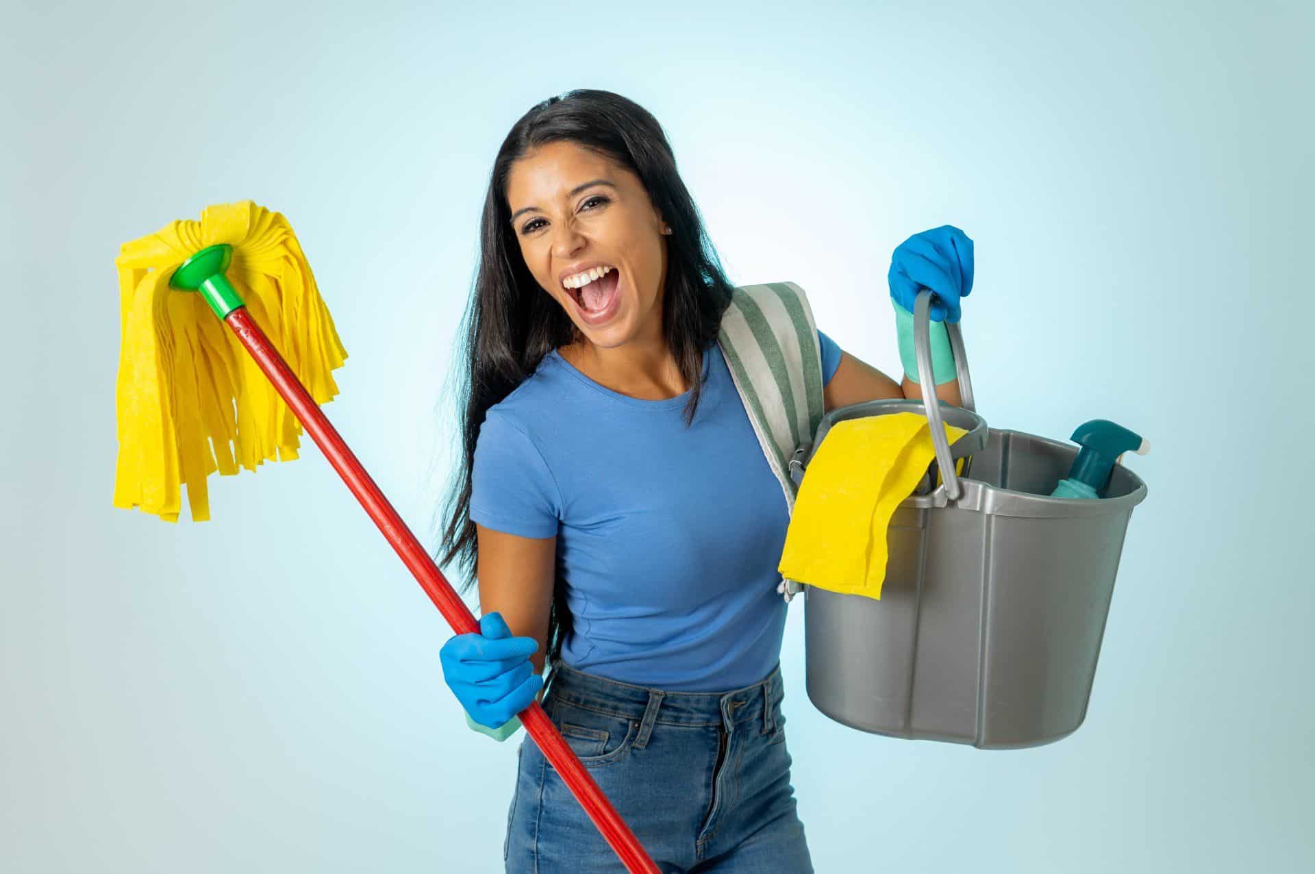 woman enthusiastically holding a mop and cleaning supplies 