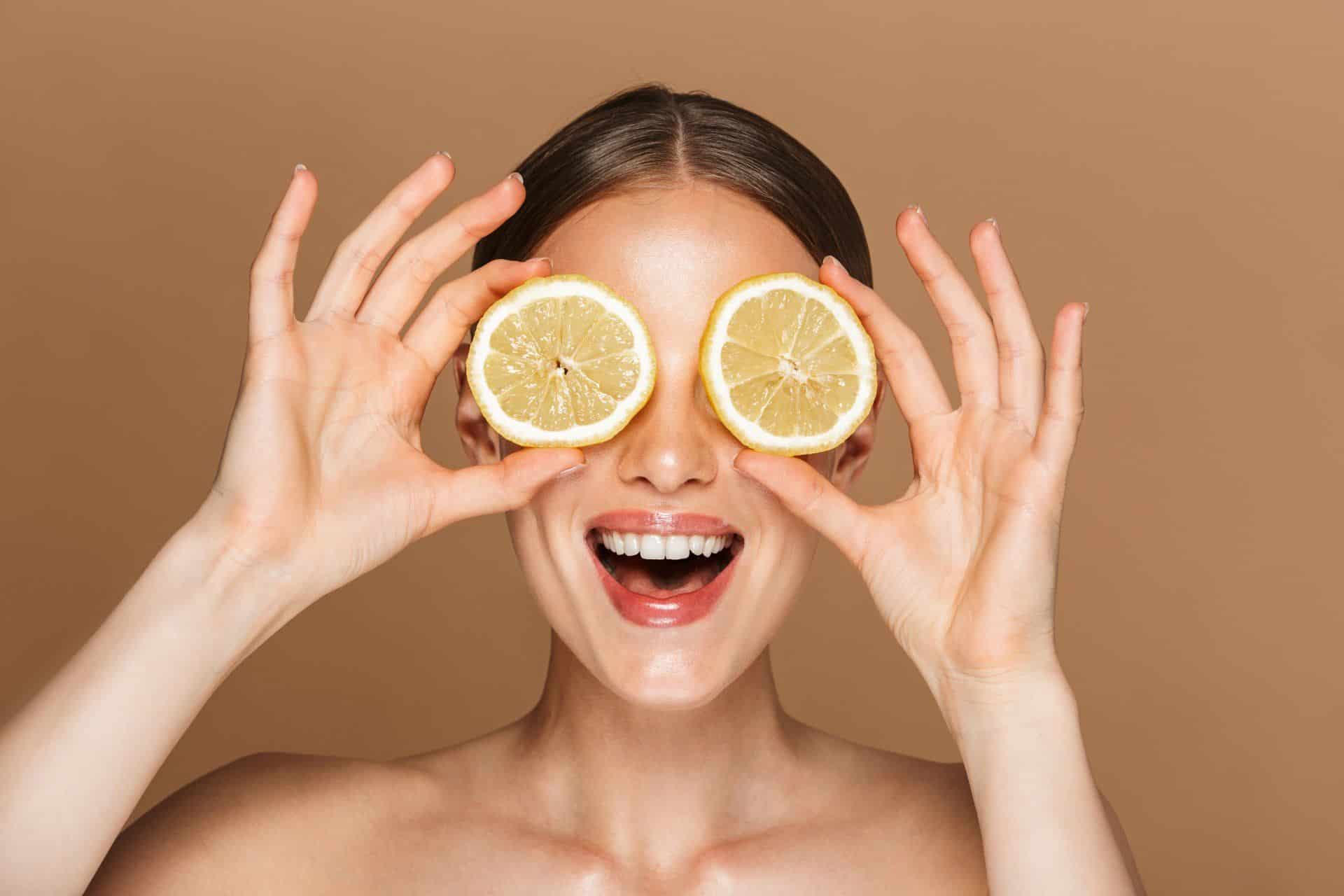 woman holding round lemon slices to her eyes