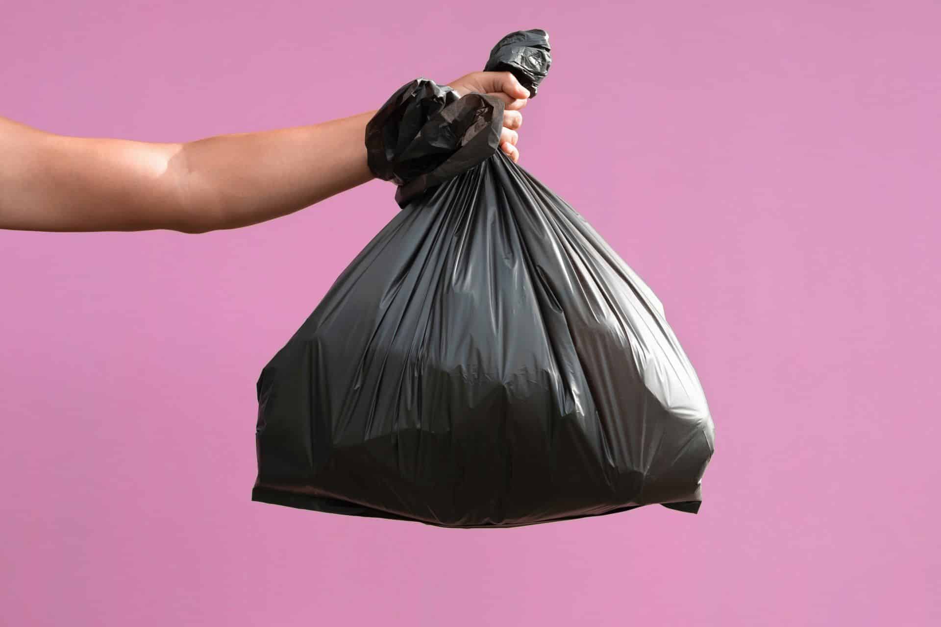someone holding a full black trash bag