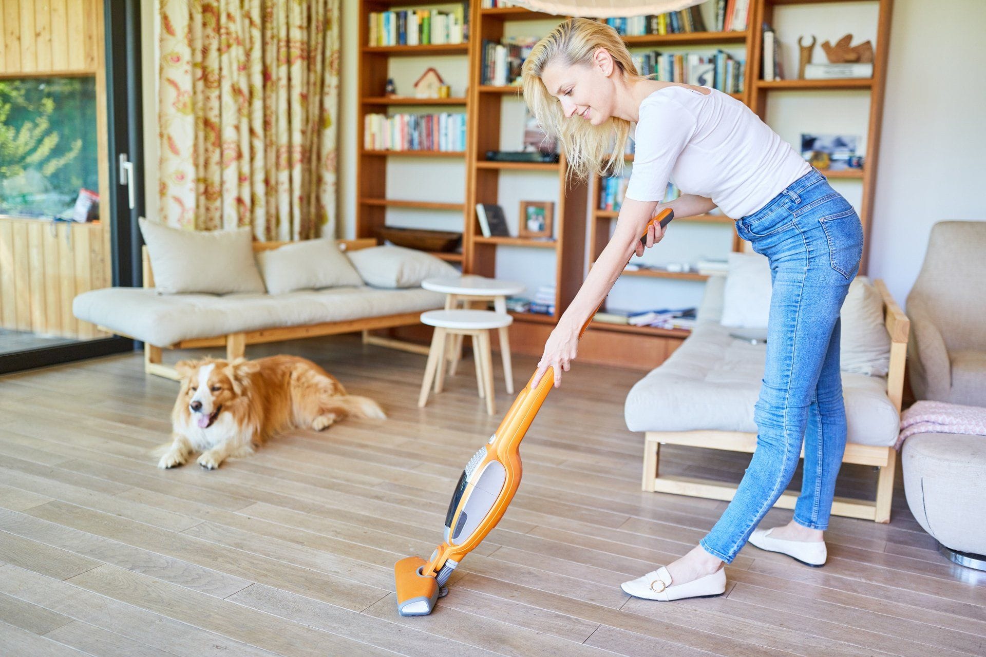 woman vacuuming with a dog in the background