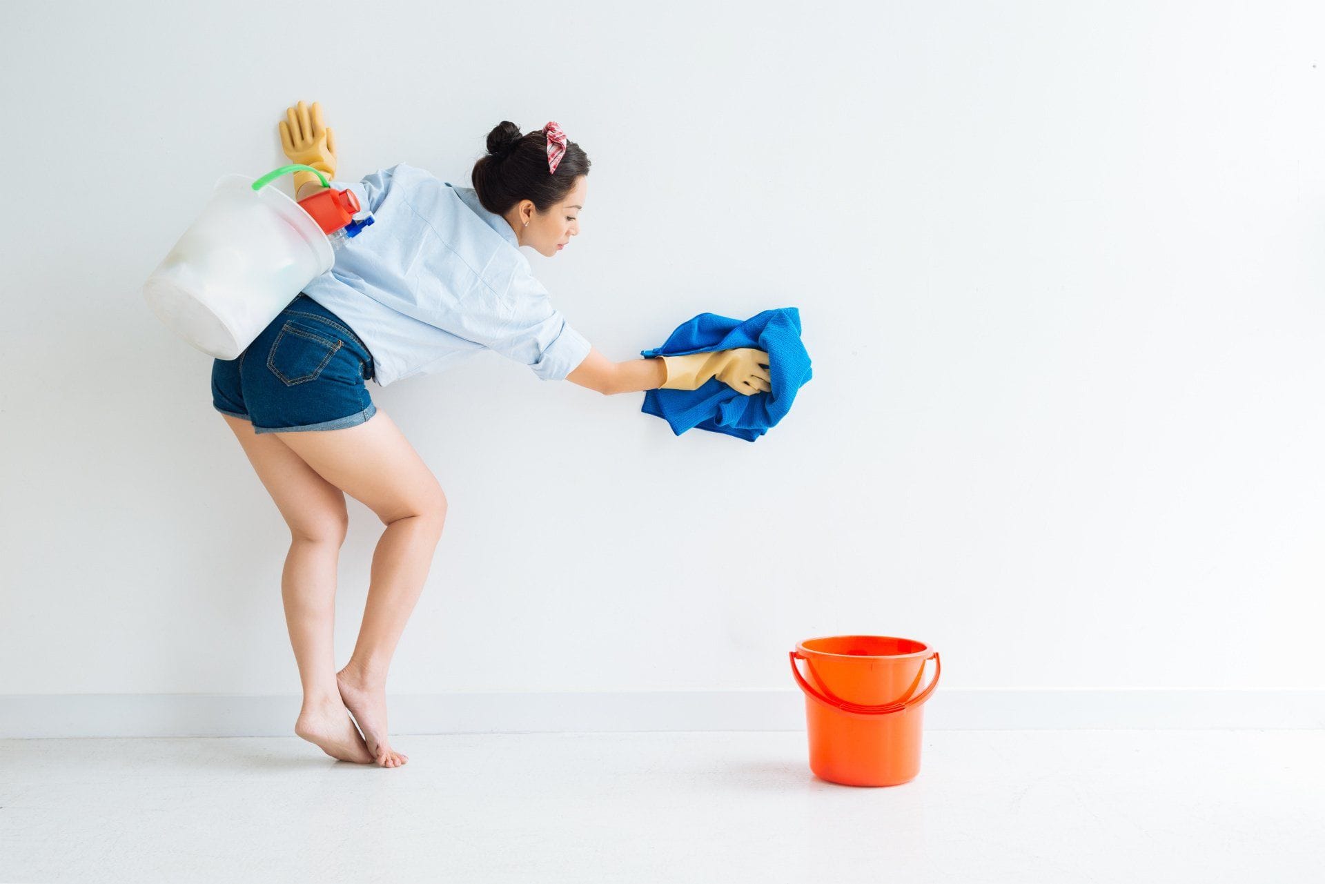woman cleaning walls with a blue towel