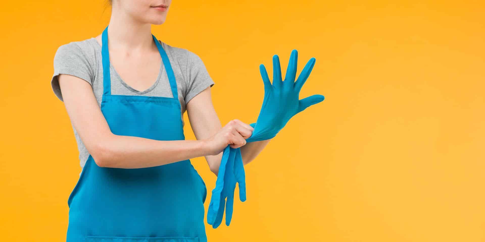 woman putting blue cleaning glove on her hand