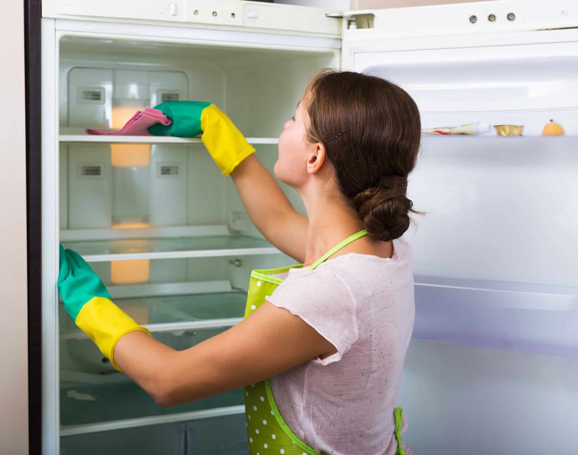 7 Cleaning Resolutions to Start Your New Year Off Right 5 woman wiping down inside of the fridge