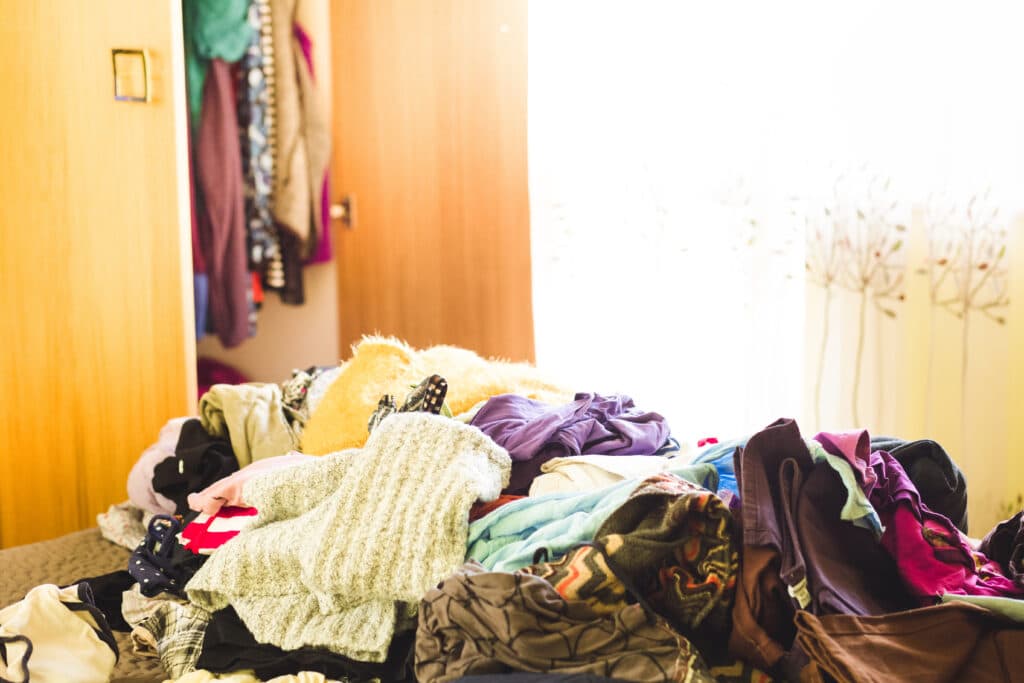 The contents of an empty hall closet piled on a bed. This is the middle of the process for hall closet organization.