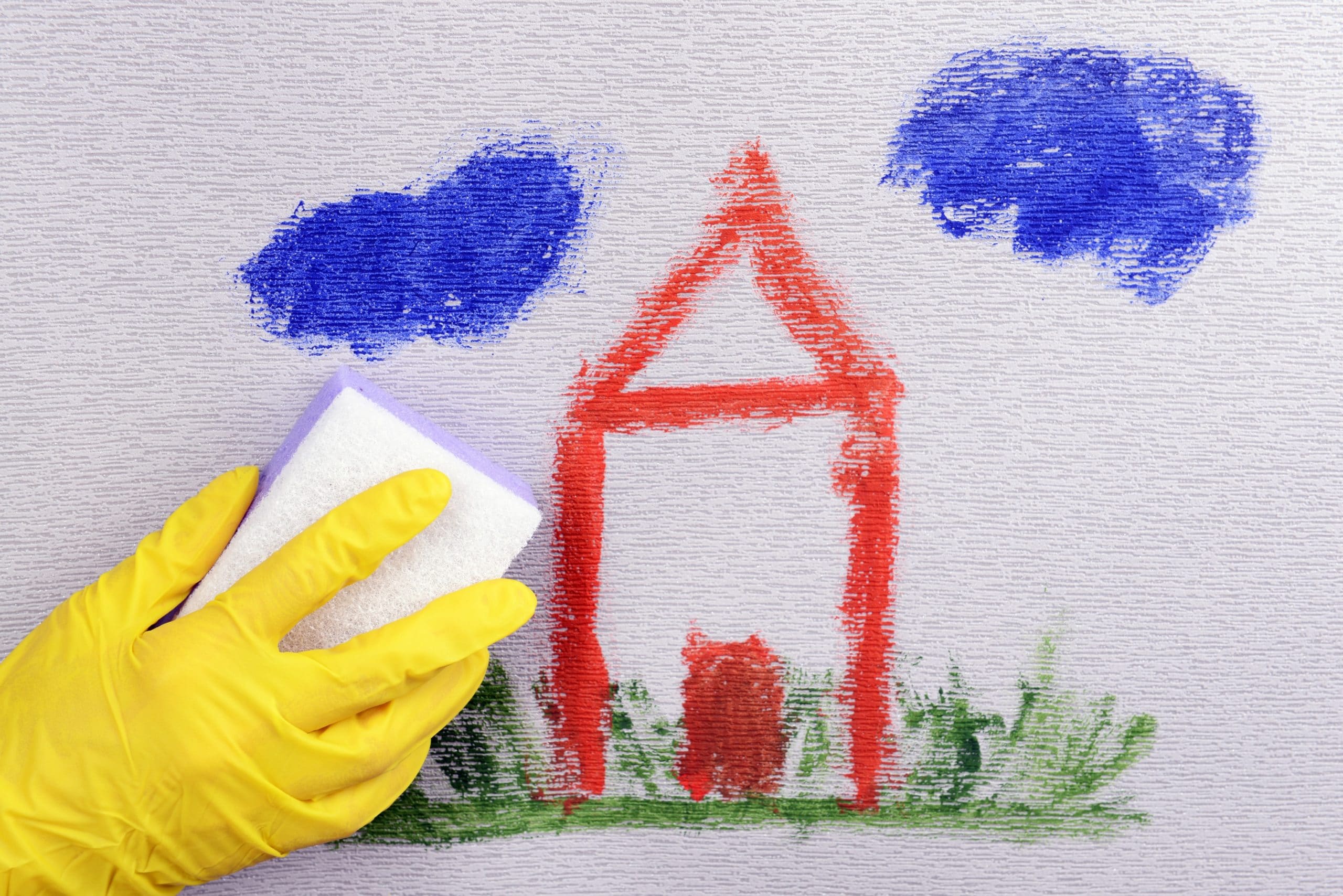 Someone cleaning crayon off of the wall with a cleaning eraser