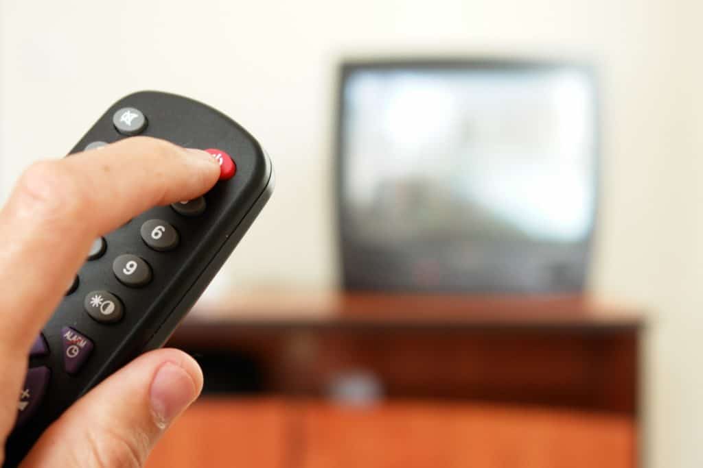 Someone turning off the TV with a remote in preparation to learn how to clean a room in 5 minutes