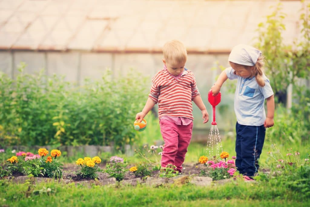 Two small children watering flowers. Yard work is one of many great chores for kids.