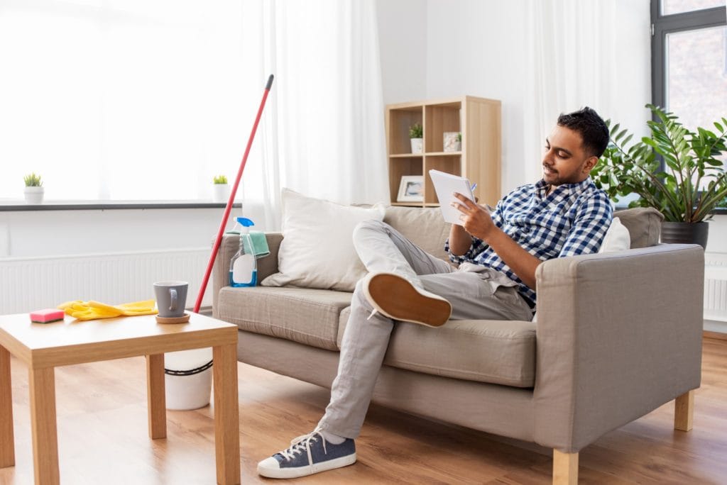 13 Things to Try and Make Cleaning Fun 10 A man sitting on a couch making a cleaning to do list