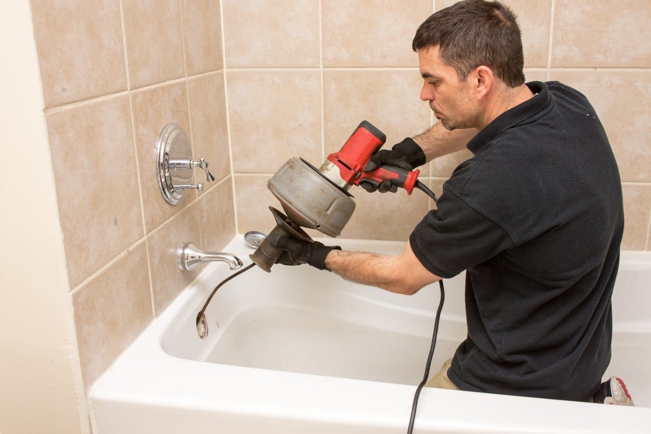 Plumber doing something to Clear Out Clogged Drains using drain snake