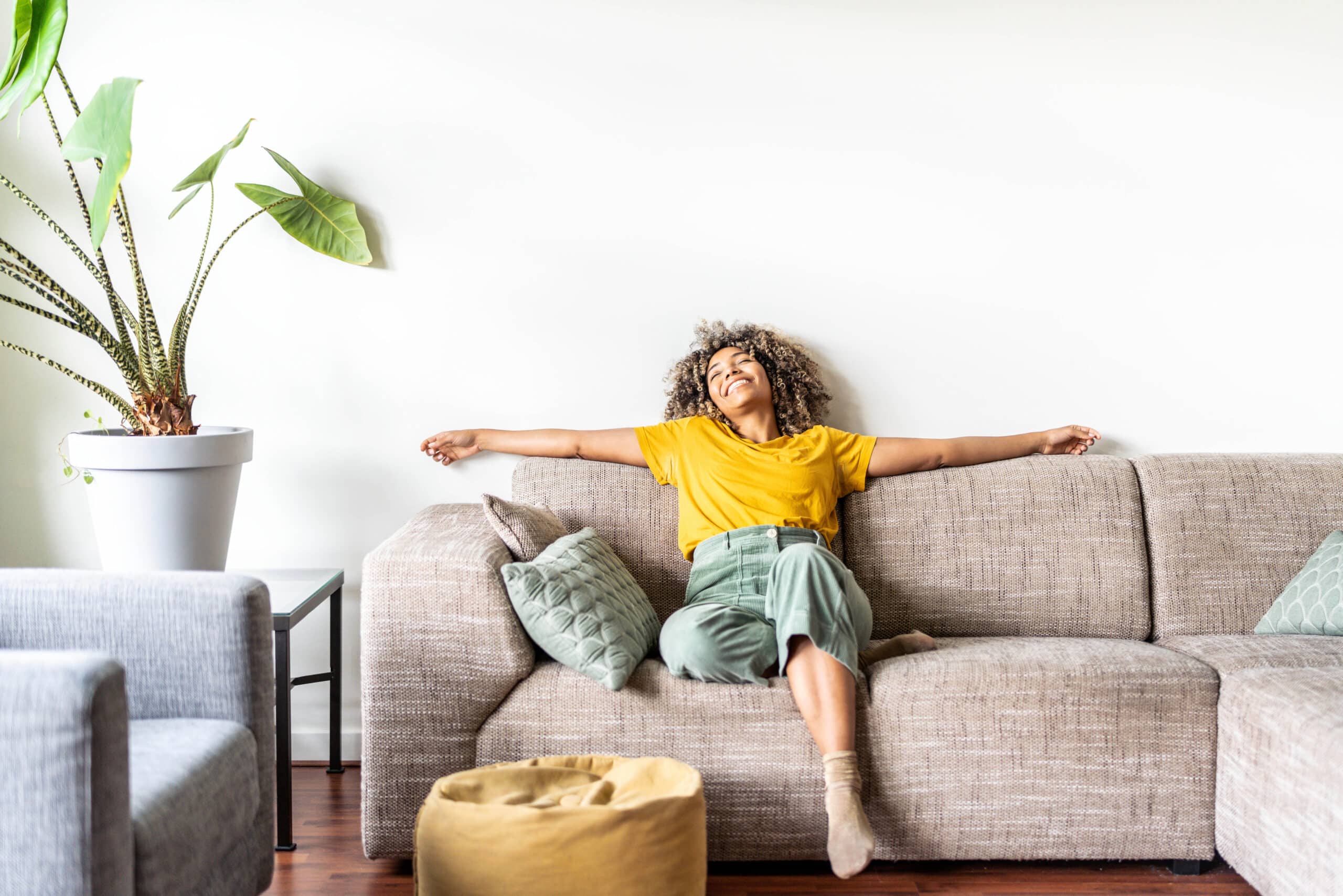 Happy afro american woman relaxing on the sofa at home - Smiling girl enjoying day off lying on the couch 